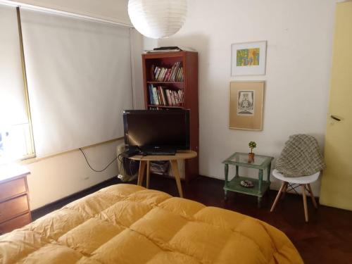 1 dormitorio con 1 cama, TV y silla en Nora Espejo en Mendoza