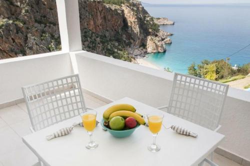 a table with a bowl of fruit and glasses of orange juice at Bella vista Suites in Karpathos Town