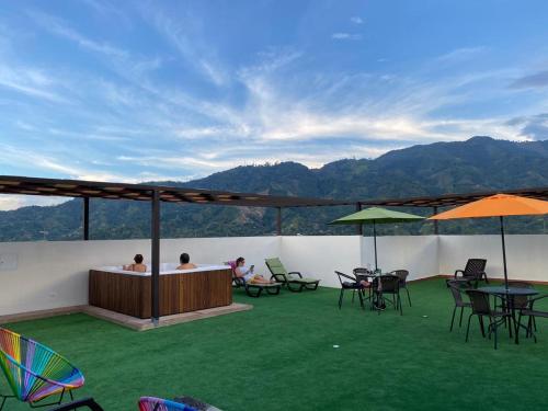 a patio with tables and chairs and a view of mountains at HOTEL VERANO in Ibagué