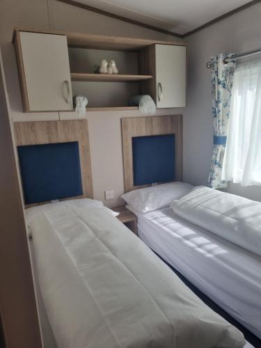 two beds in a small room with a window at Seaside Jollys in Blue Anchor