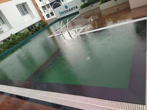 a swimming pool with two chairs in a building at Luxurious Apartment with a pool and gym near Trivandrum railway station in Trivandrum