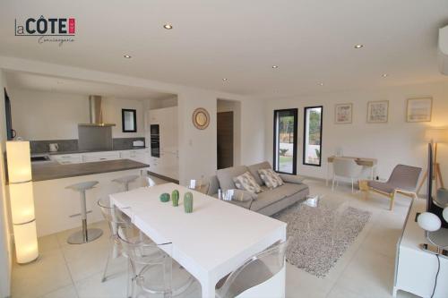 Il comprend un salon avec une table blanche et une cuisine. dans l'établissement La Pastissière - 6 couchages, à Carry-le-Rouet
