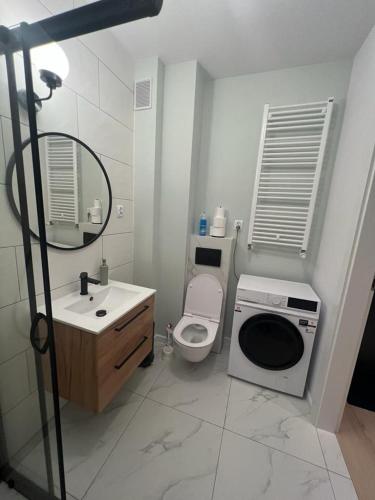 a bathroom with a toilet and a sink and a washing machine at Apartamenty Akademicka przy Onkologii 1 in Bydgoszcz