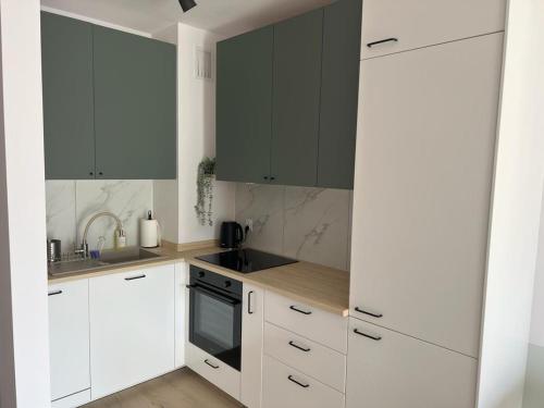 a kitchen with white cabinets and black appliances at Apartamenty Akademicka przy Onkologii 1 in Bydgoszcz