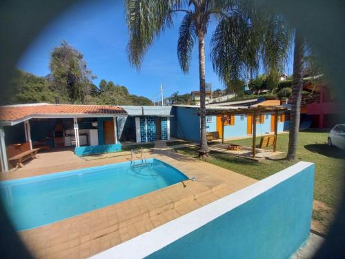 una casa con piscina y palmeras en Suites Chacara Madu, en Santo Antônio do Pinhal