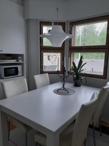 a white dining room table with white chairs and a light fixture at Peltorinne 14 in Savonlinna