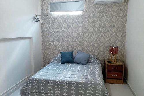 a bedroom with a bed with blue pillows on it at Malecon Rooms y Hotel in Santo Domingo