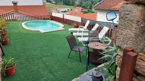 een achtertuin met een zwembad en stoelen en een tafel bij Casa do Alto das Fragas in Canedo de Basto