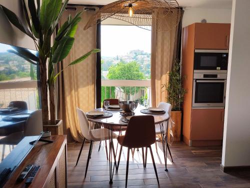 una sala da pranzo con tavolo, sedie e una finestra di L'oasis du château ! "climatisé" a Gréoux-les-Bains