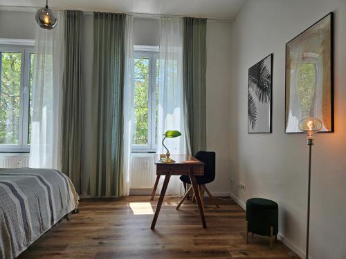 a bedroom with a bed and a desk and windows at Innenstadt Studio in Pforzheim