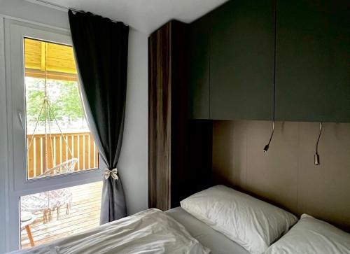 1 dormitorio con 1 cama junto a una ventana en Mobilna hiška pogled na jezero, en Velenje