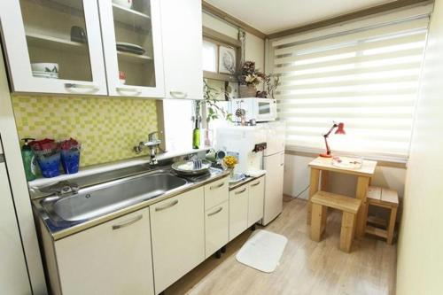 a kitchen with white cabinets and a sink and a table at Danaharu Guesthouse in Jeonju
