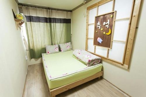 Cama pequeña en habitación con ventana en Danaharu Guesthouse, en Jeonju