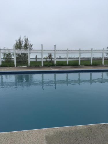 a swimming pool with a white fence in the background at Auberge Janine du Havre in Shippagan