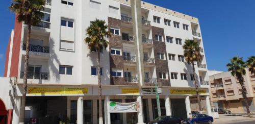 a large white building with palm trees in front of it at La Remaz 35 in El Jadida