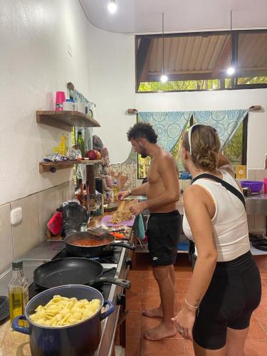 a man and a woman preparing food in a kitchen at Luminosa Uvita Hostel in Uvita