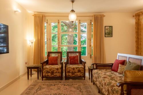 a living room with two chairs and a window at BluSalzz Villas - The Pine Tree, Dalhousie - Himachal Pradesh in Dalhousie