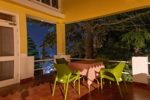 a patio with a table and chairs on a balcony at BluSalzz Villas - The Pine Tree, Dalhousie - Himachal Pradesh in Dalhousie