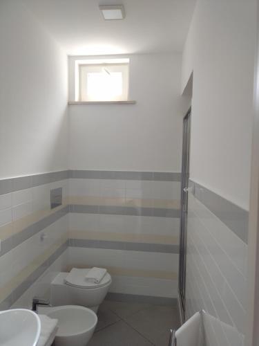 a bathroom with a toilet and two sinks and a window at LA REGGIA APARTMENTS MILAZZO in Milazzo