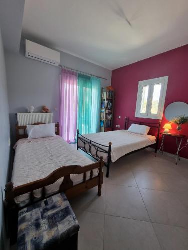 a bedroom with two beds and a purple wall at Vlasis home in Nafpaktos