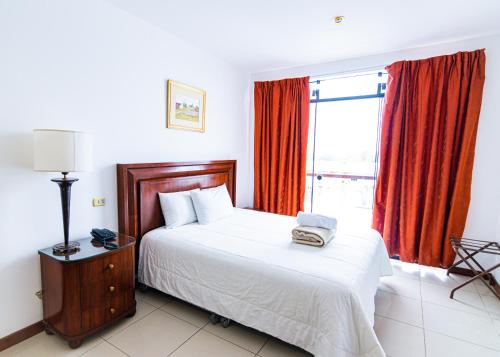 um quarto com uma cama e uma janela com cortinas vermelhas em Mc Hotel Ica em Ica