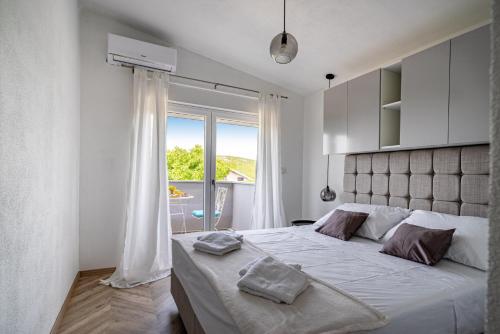 - une chambre blanche avec un grand lit et une fenêtre dans l'établissement Villa Diva, à Stankovci