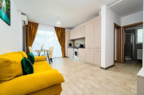 uma sala de estar com um sofá amarelo e uma cozinha em Andreas - Pool & Spa Beach Resort em Mamaia Nord – Năvodari