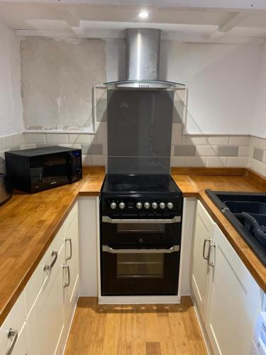a kitchen with a black stove and a microwave at Beautiful studio apartment in Pembrokeshire