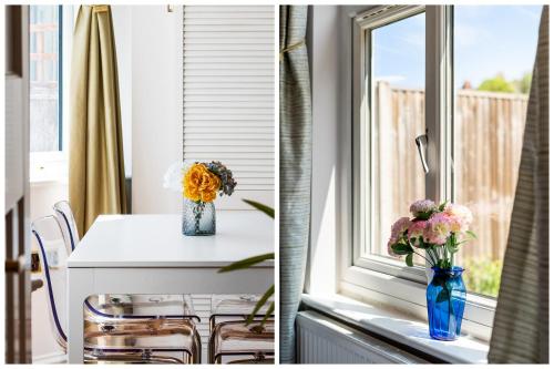 ein Küchenfenster mit einem Tisch und Blumen in einer blauen Vase in der Unterkunft Lovely garden apartment in Wimbledon Town Centre with private parking by Wimbledon Holiday Lets in London