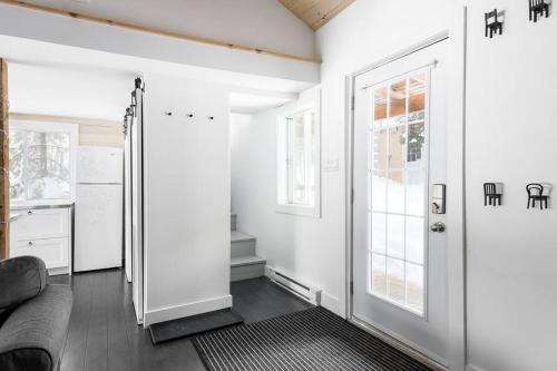 een woonkamer met een bank en een deur bij Nature et tranquilité à une heure de Montréal, vue sur le lac in Saint-Calixte