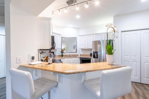a kitchen with white cabinets and a counter with white chairs at One Club Gulf Shores in Gulf Shores