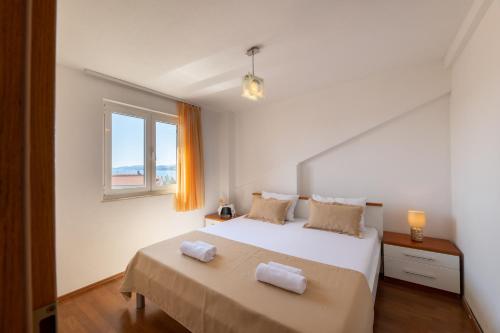 a white bedroom with a bed and a window at Apartments Vranjić in Trogir