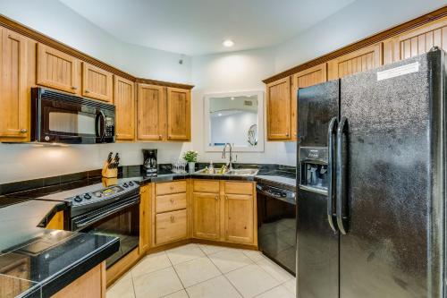 a kitchen with wooden cabinets and a stainless steel refrigerator at One Club Gulf Shores in Gulf Shores