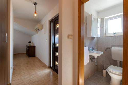 a bathroom with a toilet and a sink and a window at Apartments Vranjić in Trogir