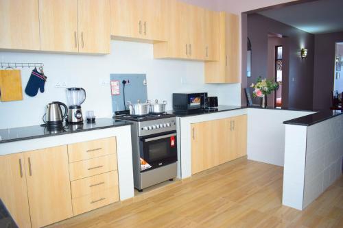 a kitchen with wooden cabinets and a stove top oven at Ilala House, Voi - 2 bed, 2 bath in Voi