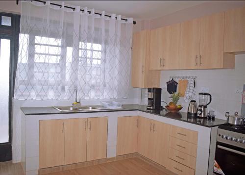 a kitchen with wooden cabinets and a sink at Ilala House, Voi - 2 bed, 2 bath in Voi