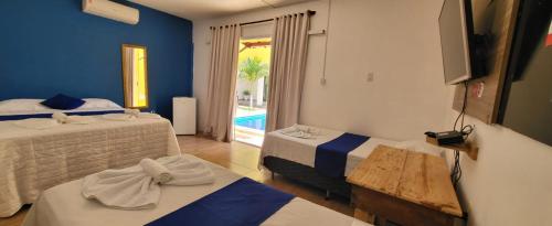 a room with two beds and a view of a pool at pousada Amarante praia 1 in São Miguel do Gostoso