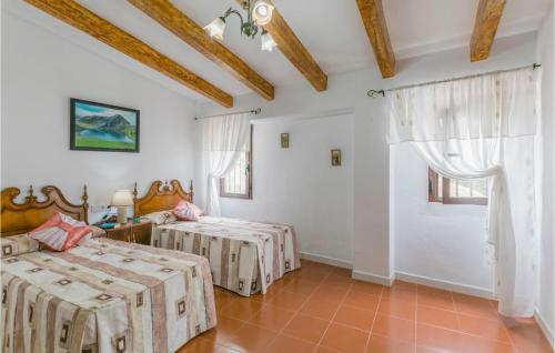 Duas camas num quarto com paredes brancas e tectos em madeira em 4 Bedroom Stunning Home In Villanueva De Algaidas em Villanueva de Algaidas