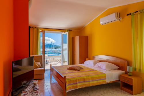 een slaapkamer met een bed, een televisie en een balkon bij Apartments Mikulić in Rogoznica