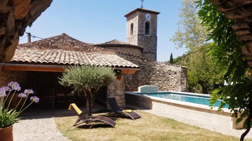 une maison avec une piscine et un bâtiment avec une tour d'horloge dans l'établissement Maison de caractère La Calade, à Rochecolombe