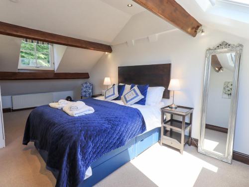 a bedroom with a bed with a blue comforter and a mirror at Stablemans Cottage at Stepping Stones in Ambleside