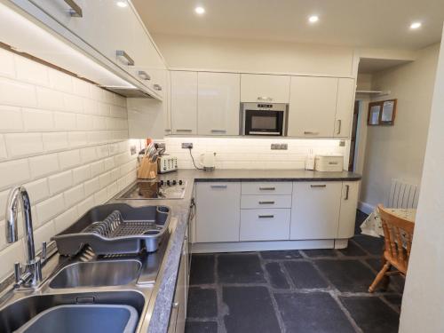 a kitchen with white cabinets and a sink at Slaters Rest in Chapel Stile