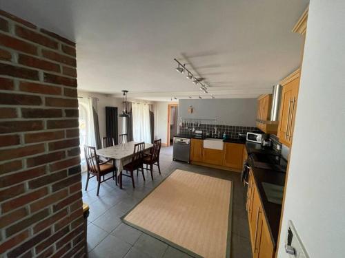 a kitchen with a table and chairs and a brick wall at A stunning converted barn offering country life. in Chewton Mendip