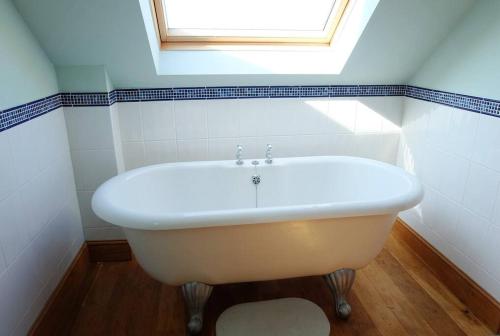 uma banheira branca na casa de banho com uma janela em A stunning converted barn offering country life. em Chewton Mendip