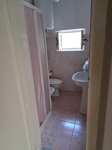 baño con 2 aseos, lavamanos y ventana en La casa Dei Dadi en Milazzo