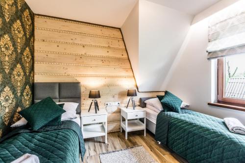 a room with two beds and a desk and a window at Apartamenty Tradycja in Zakopane