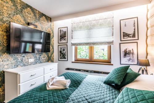 a bedroom with a green bed and a flat screen tv at Apartamenty Tradycja in Zakopane