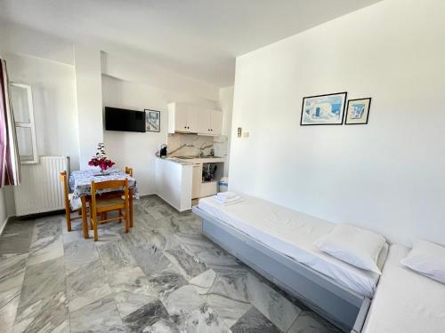 Habitación blanca con cama, mesa y cocina en Country House Apartments, en Ios Chora