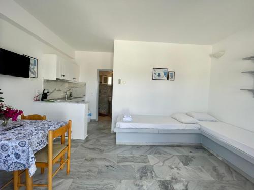Country House Apartments في إيوس خورا: غرفة بيضاء مع سرير وطاولة