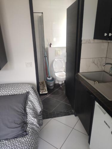 La salle de bains est pourvue de toilettes, d'une chaise et d'un lavabo. dans l'établissement Studio bien situé, à Eybens